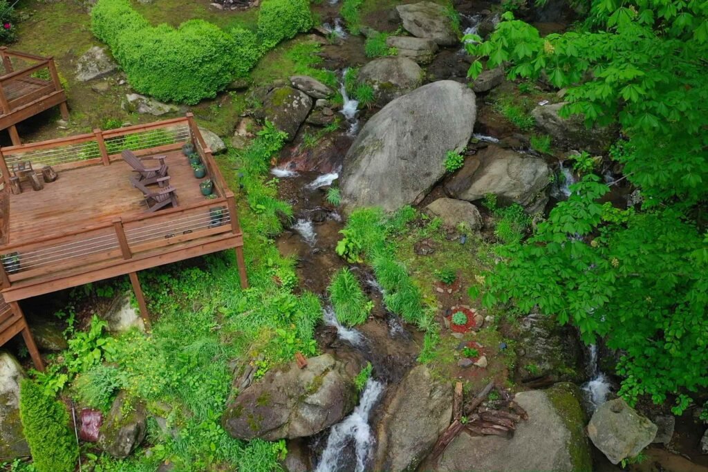 drone above patio and island looking up Secluded forest waterfall and clear mountain stream on the grounds of Windows Over Waterfalls, a private nature retreat and cabin stay near Hot Springs, NC.