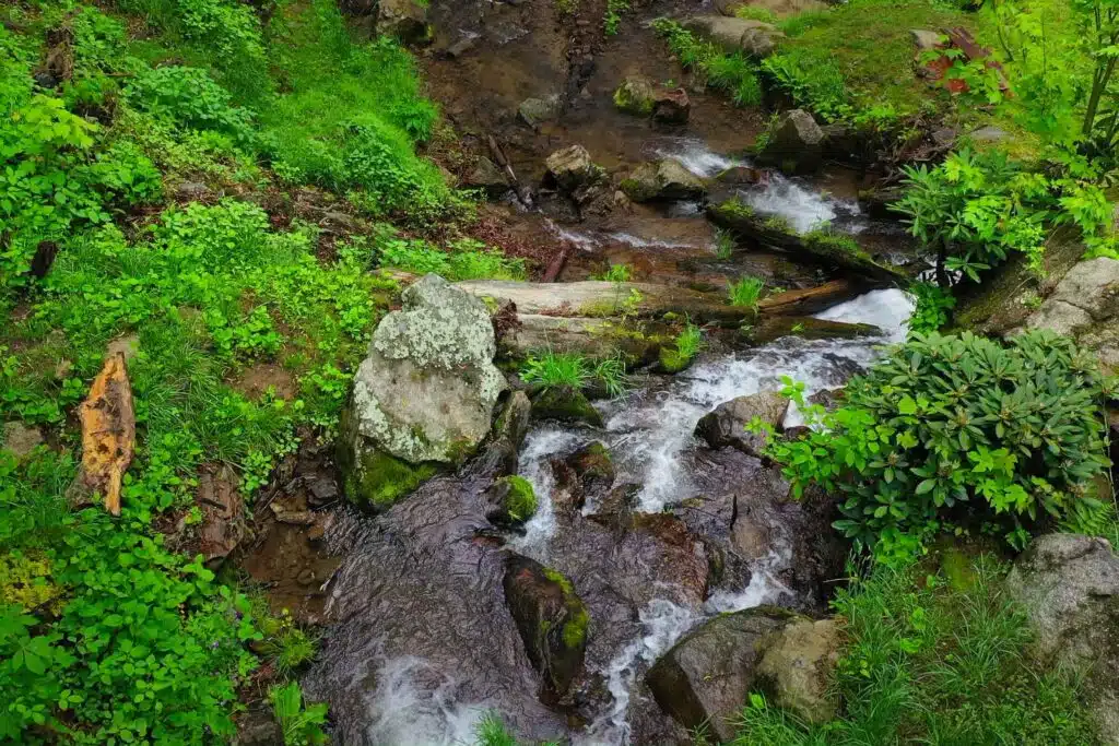 drone big falls from straight up Private waterfall flowing through boulder-lined creek at Windows Over Waterfalls, a secluded luxury cabin retreat near Hot Springs, NC.