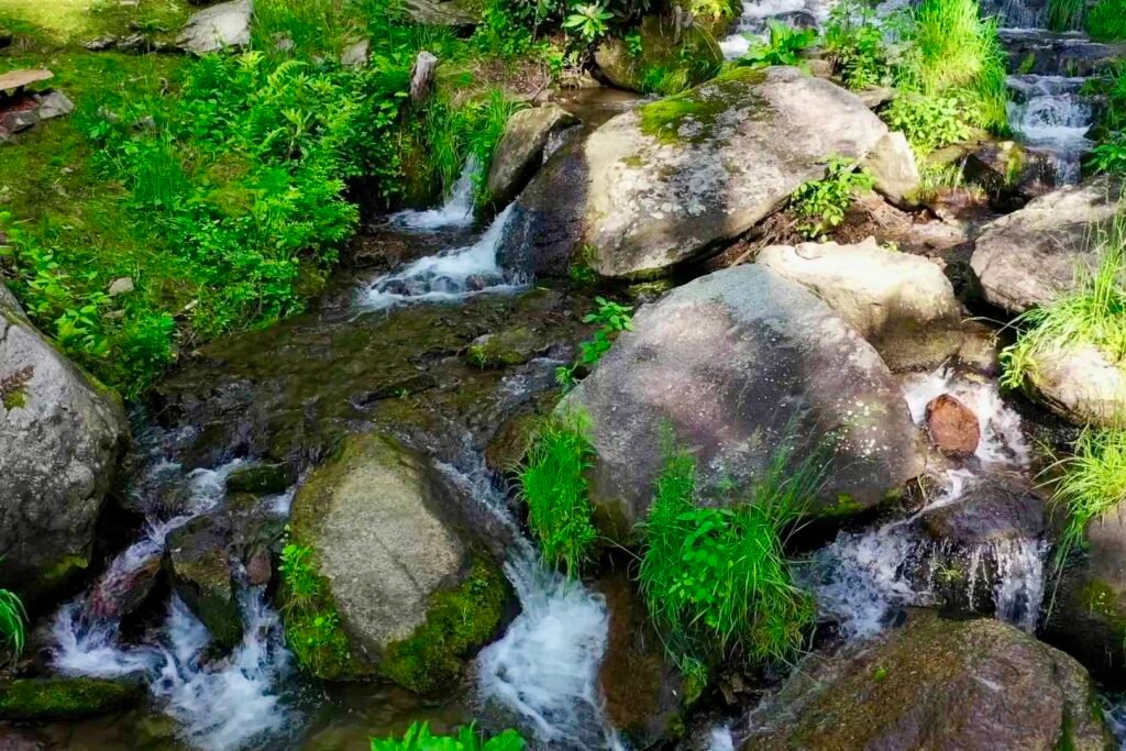 drone cascades above firepit looking up Scenic waterfall and rocky creek behind Windows Over Waterfalls romantic getaway cabin in NC