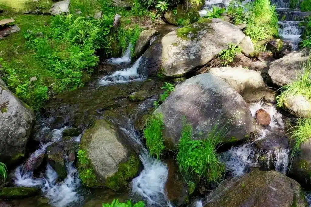 drone cascades above firepit looking up Scenic waterfall and rocky creek behind Windows Over Waterfalls romantic getaway cabin in NC