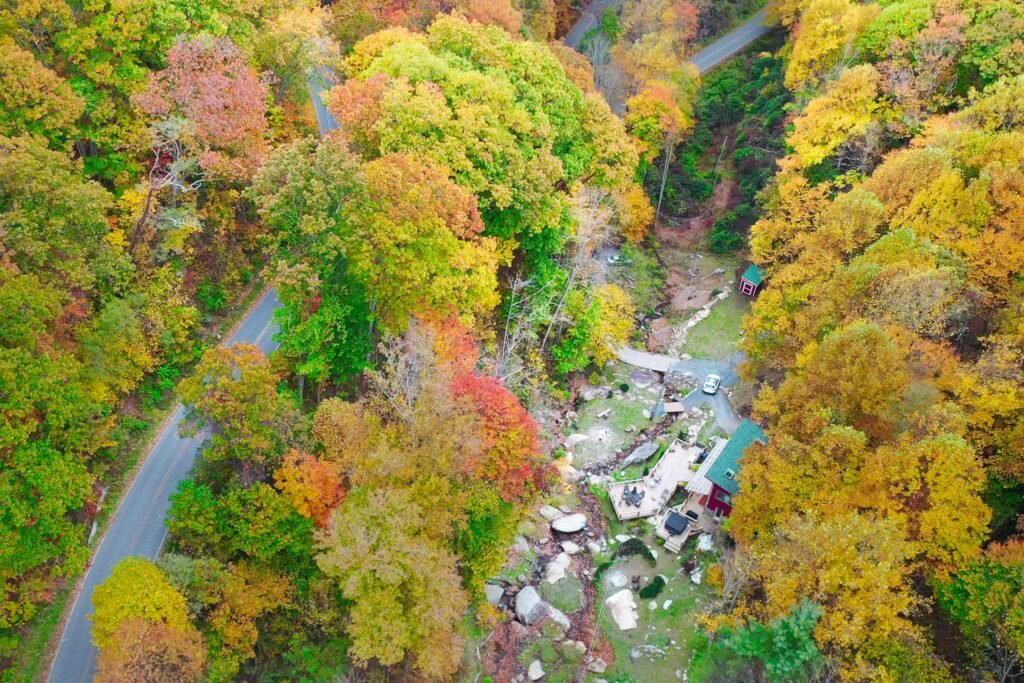 drone foliage above house with road Scenic creek and waterfall landscape at a secluded cabin rental in the North Carolina mountains