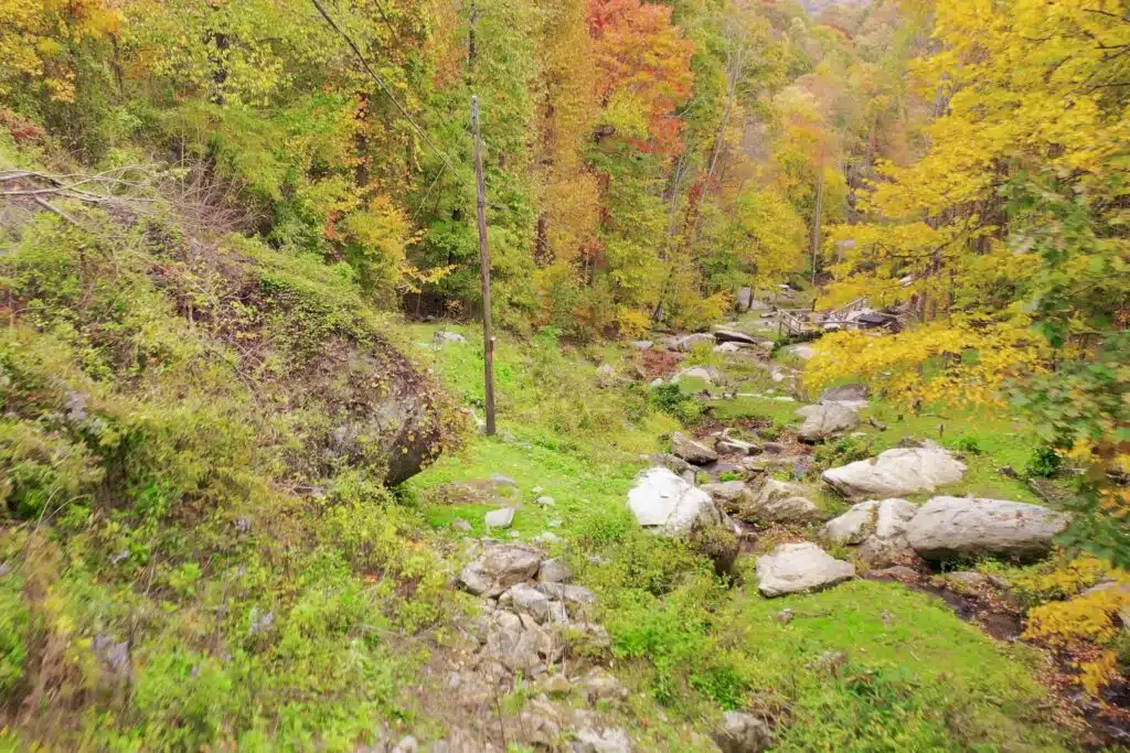drone foliage flat above flat rock looking down Waterfall stream running past large boulders on a private cabin property in the Blue Ridge Mountains