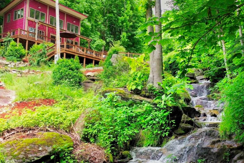 drone house from bridge far creek Small waterfall flowing through mossy boulders at a secluded mountain cabin near Hot Springs NC