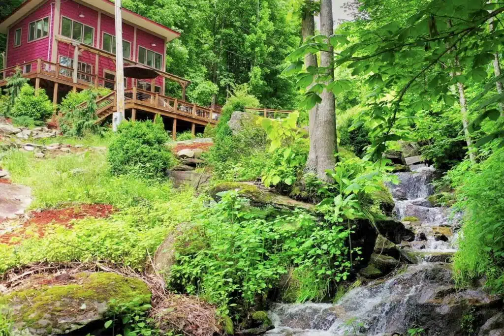 drone house from bridge far creek Small waterfall flowing through mossy boulders at a secluded mountain cabin near Hot Springs NC
