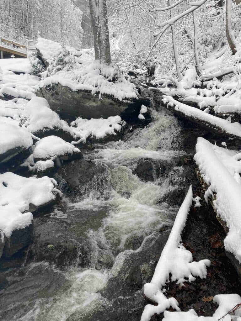 Snow-covered creek and frozen waterfall view at Windows Over Waterfalls in Hot Springs, NC